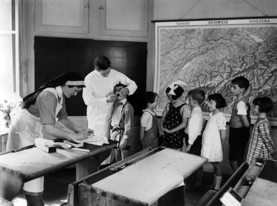 Germaine Golay (volée 1923), lors de la visite du dentiste scolaire. Elle tient les registres médicaux afin d’assurer la suite des traitements, si nécessaire.